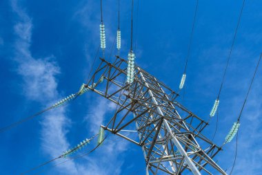Yüksek voltajlı elektrik hatları mavi gökyüzü bulutlu destekler. Elektrik Sanayi