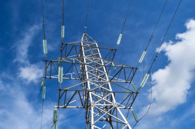 Yüksek voltajlı elektrik hatları mavi gökyüzü bulutlu destekler. Elektrik Sanayi
