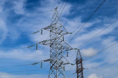 Yüksek voltajlı elektrik hatları mavi gökyüzü bulutlu destekler. Elektrik Sanayi