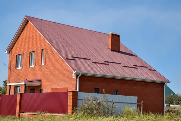 Detached house with a roof made of steel sheets. Roof metal sheets. Modern types of roofing materials.