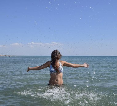 Deniz suyu içinde sprinkles. Uçan sprey su kadar atar. Kız siyah saçlı ve bir banyo ile deniz hoşlanır.