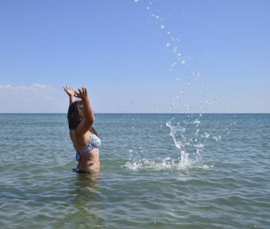 Deniz suyu içinde sprinkles. Uçan sprey su kadar atar. Kız siyah saçlı ve bir banyo ile deniz hoşlanır.