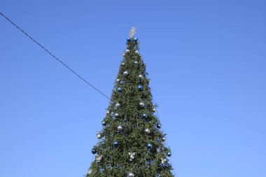 Süslemeleri yılbaşı ağacı. Tinsel ve oyuncaklar, topları ve diğer süslemeleri Noel Noel ayakta açık havada ağaç.