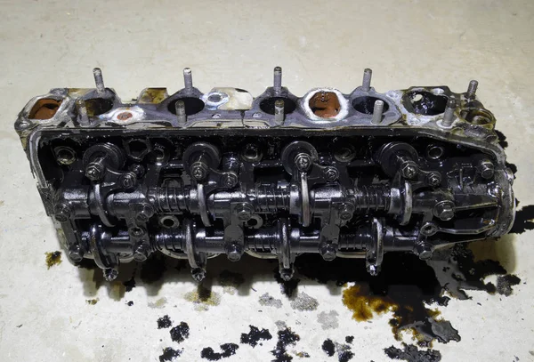 The head of the block of cylinders. The head of the block of cylinders removed from the engine for repair. Parts in engine oil. Car engine repair in the service.