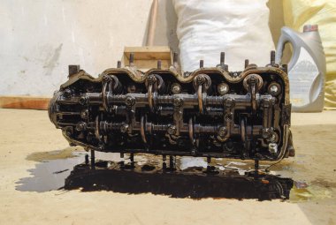 Silindir bloğunun başı. Silindir bloğunun başı tamir için motordan çıkarıldı. Motor yağının parçaları. Araç motoru tamiri serviste..