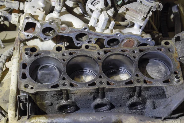 The cylinder block of the four-cylinder engine. Disassembled motor vehicle for repair. Parts in engine oil. Car engine repair in the service.