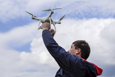 Quadrocopter göğe kaldırdı onun kollarında bir adam. Beyaz bir drone uçuş için hazırlanıyor.