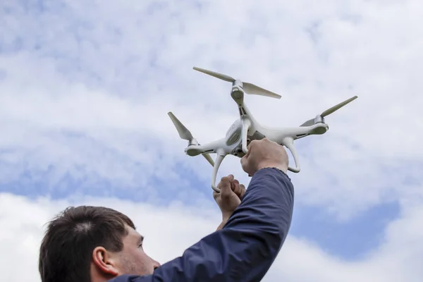 Un homme avec un quadrocopter dans les bras levés vers le ciel. Un drone blanc est en préparation pour le vol . — Photo