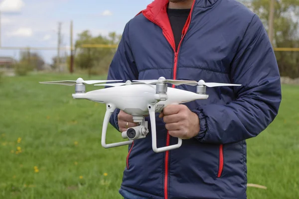 A man with a quadrocopter in his hands. A white drone is being prepared for the flight. Phantom.