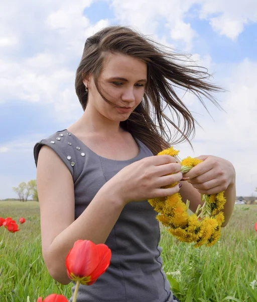 A girl with a wreath of dandelions in her hands. Field of tulips — Stock Photo, Image