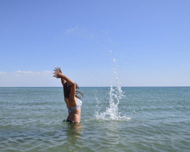 Deniz suyu içinde sprinkles. Uçan sprey su kadar atar. Kız siyah saçlı ve bir banyo ile deniz hoşlanır.
