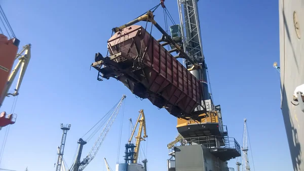 Transporte de vagones de mercancías en el puerto por una grúa portuaria. Operaciones de elevación de carga. Puerto industrial . — Foto de Stock