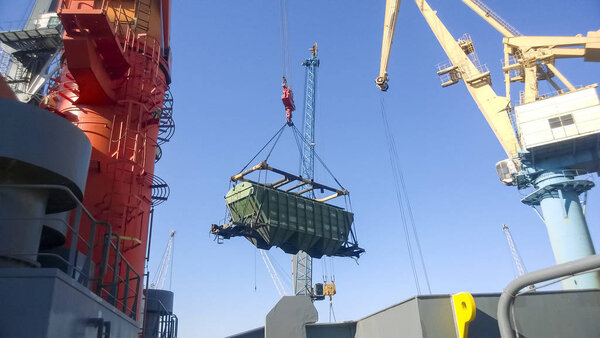 Novorossiysk, Russia - August 11, 2016: Moving freight railway car in the port by a port crane. Cargo lifting operations. Industrial port.