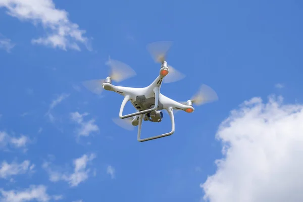 Drönare Dji Phantom 4 under flygning. Quadrocopter mot blå himmel med vita moln. Flyg av copter i himlen. — Stockfoto