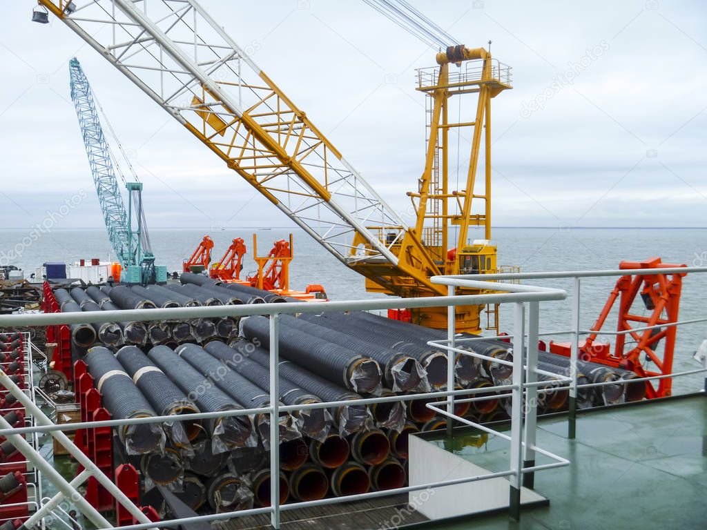 The deck lay barge. Pipes and Lifting cranes on the ship. Equipment for laying a pipeline on the seabed