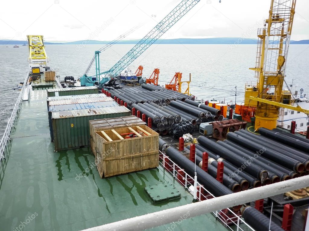 The deck lay barge. Pipes and Lifting cranes on the ship. Equipment for laying a pipeline on the seabed