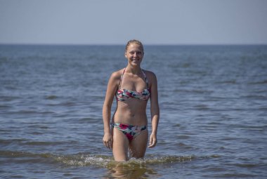 Sarışın kız bikinili deniz suyu dışarı geliyor. Deniz arka plan üzerinde renkli bikinili güzel genç kadın.