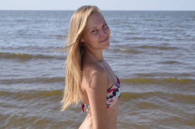 Sahilde bikinili sarışın kız. Deniz arka plan üzerinde renkli bikinili güzel genç kadın.