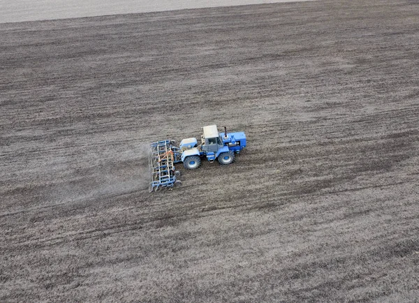 De trekker plows het veld. Onder het zaaien, is de bodem losgemaakt op het veld. — Stockfoto