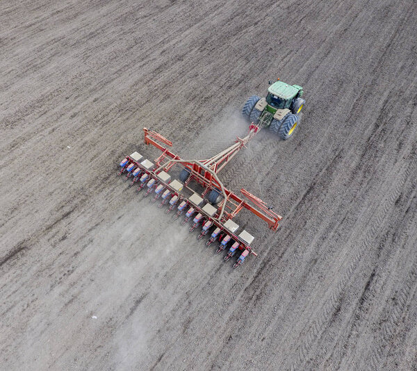 Посев кукурузы. Трактор с сеялкой на поле. Использование сеялки для посадки кукурузы
.