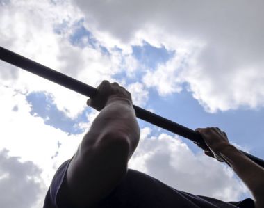 Çubuğunda eller yakın çekim. Adam kendini çubuğunda çeker. Temiz havada spor oynarken. Yatay çubuk