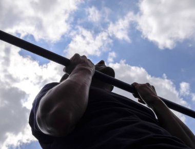 Adam kendini barın üzerine çekti. Temiz havada spor yapmak için. Yatay çubuk