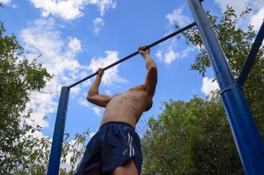 Adam kendini barın üzerine çekti. Temiz havada spor yapmak için. Yatay çubuk
