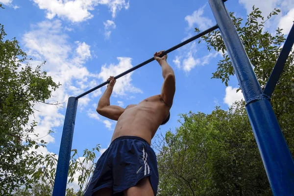 Adam kendini barın üzerine çekti. Temiz havada spor yapmak için. Yatay çubuk