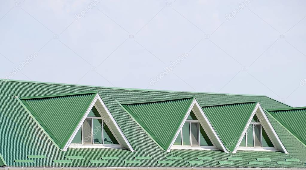 The house with plastic windows and a green roof of corrugated sheet. Green roof of corrugated metal profile and plastic windows.