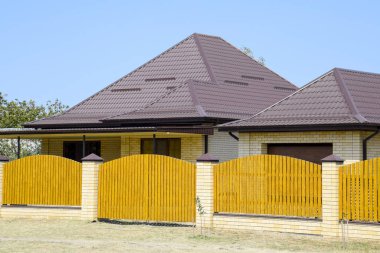 Oluklu metal profil çatısı ve ahşap çit tuğla ev. Güzel manzara cephe. Stil tasarım