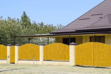 Oluklu metal profil çatısı ve ahşap çit tuğla ev. Güzel manzara cephe. Stil tasarım.