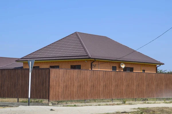Bir ev ile bir metal çatı oluklu ve gauve çit kahverengi bir metal profilden yapılmış