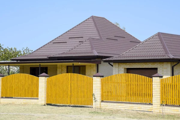 Oluklu metal profil çatısı ve ahşap çit tuğla ev. Güzel manzara cephe. Stil tasarım