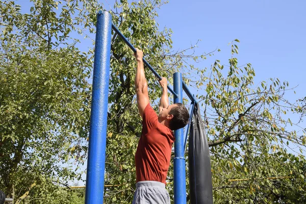 Adam kendini çubuğunda çeker. Temiz havada spor oynarken. Bahçedeki ev yapımı yatay çubuk.