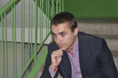 Genç adam bir ceket ve gömlek bir apartman merdiven ve merdivenler zemin karşı