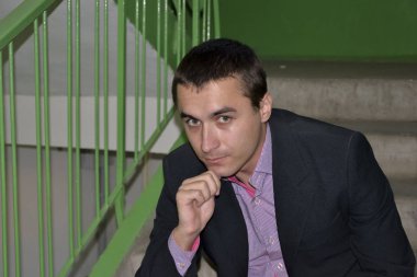 Genç adam bir ceket ve gömlek bir apartman merdiven ve merdivenler zemin karşı