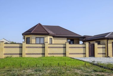 Bir çit ve gates ile tuğla ev. Yeni bir İnşaatlı çit görünümünü