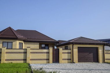 Bir çit ve gates ile tuğla ev. Görünümü yeni bir İnşaatlı çit ve tuğla ve oluklu metal yapılmış bir ev