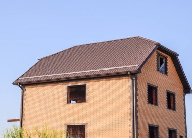 Plastik pencere ve oluklu levha çatısı olan ev. Çatı metal profil dalgalı şeklin üzerinde plastik penceresi olan ev.