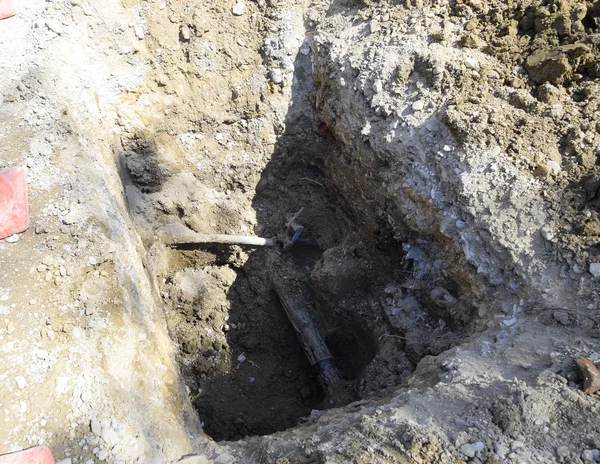 Zarar görmüş bir boru hattı ile kazılmış bir çukur. İletişim tamiri