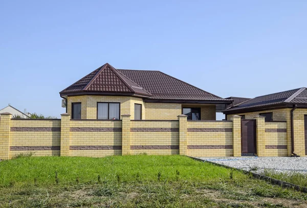 Bir çit ve gates ile tuğla ev. Yeni bir İnşaatlı çit görünümünü