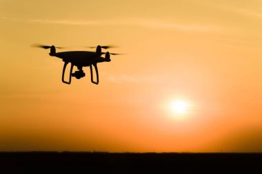 Quadrocopters siluet güneşin arka planı. Akşam gökyüzünde uçan uçaklar.