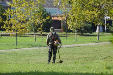 Krasnodar, Rusya - 12 Ekim 2016: bir işçi bir benzin fırça ile çim biçme. Düzeltici. Balık tutma çizgi düzeltici kullanarak yeşil çim biçme. Uygulama & bıyık kesme makineleri.