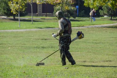 Krasnodar, Rusya - 12 Ekim 2016: bir işçi bir benzin fırça ile çim biçme. Düzeltici. Balık tutma çizgi düzeltici kullanarak yeşil çim biçme. Uygulama & bıyık kesme makineleri.