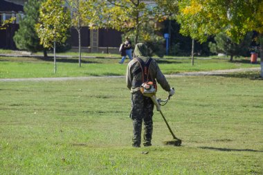 Krasnodar, Rusya - 12 Ekim 2016: bir işçi bir benzin fırça ile çim biçme. Düzeltici. Balık tutma çizgi düzeltici kullanarak yeşil çim biçme. Uygulama & bıyık kesme makineleri.