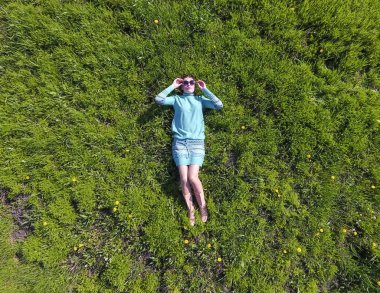 ' In bahçesinde turkuaz elbiseli bir kız yatıyor. otların uzanmış güzel kız