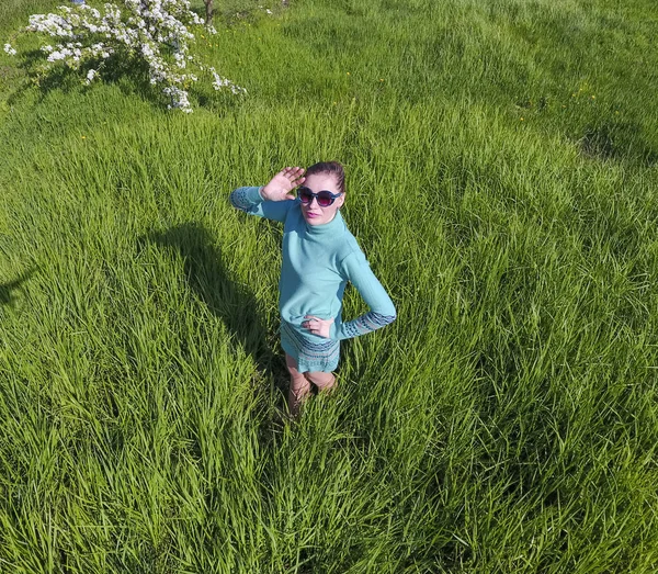 緑の草の芝生の上のライト グリーンのドレスの少女。高さから上からの人間観. — ストック写真