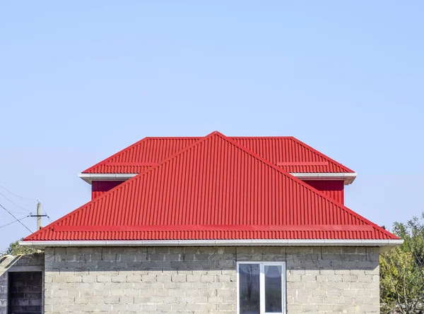 Telhado ondulado vermelho. Casa do bloco de cimento. Casa com janelas de plástico e telhado de folha ondulada — Fotografia de Stock