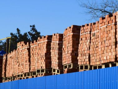 Kırmızı tuğla küpler halinde yığılmış. Ambar tuğla. Depolama aracınızda ürünleri