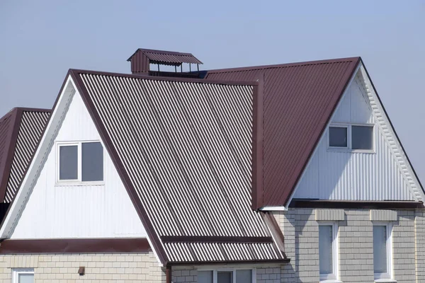 Het huis is met een zolder en een gecombineerde dak. Huis met kunststof ramen en een bruin dak van golfplaten — Stockfoto